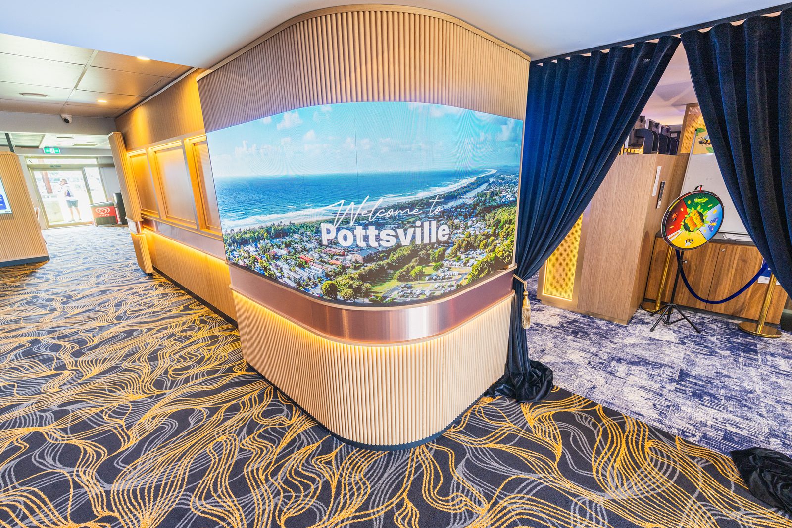 Curved LED wall installed by Cyberry at Pottsville Beach Sports Club, showing a Welcome to Pottsville aerial